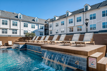 a pool with a waterfall and a row of lounge chairs in front of a building  at Harbor Pointe, New Jersey, 07002